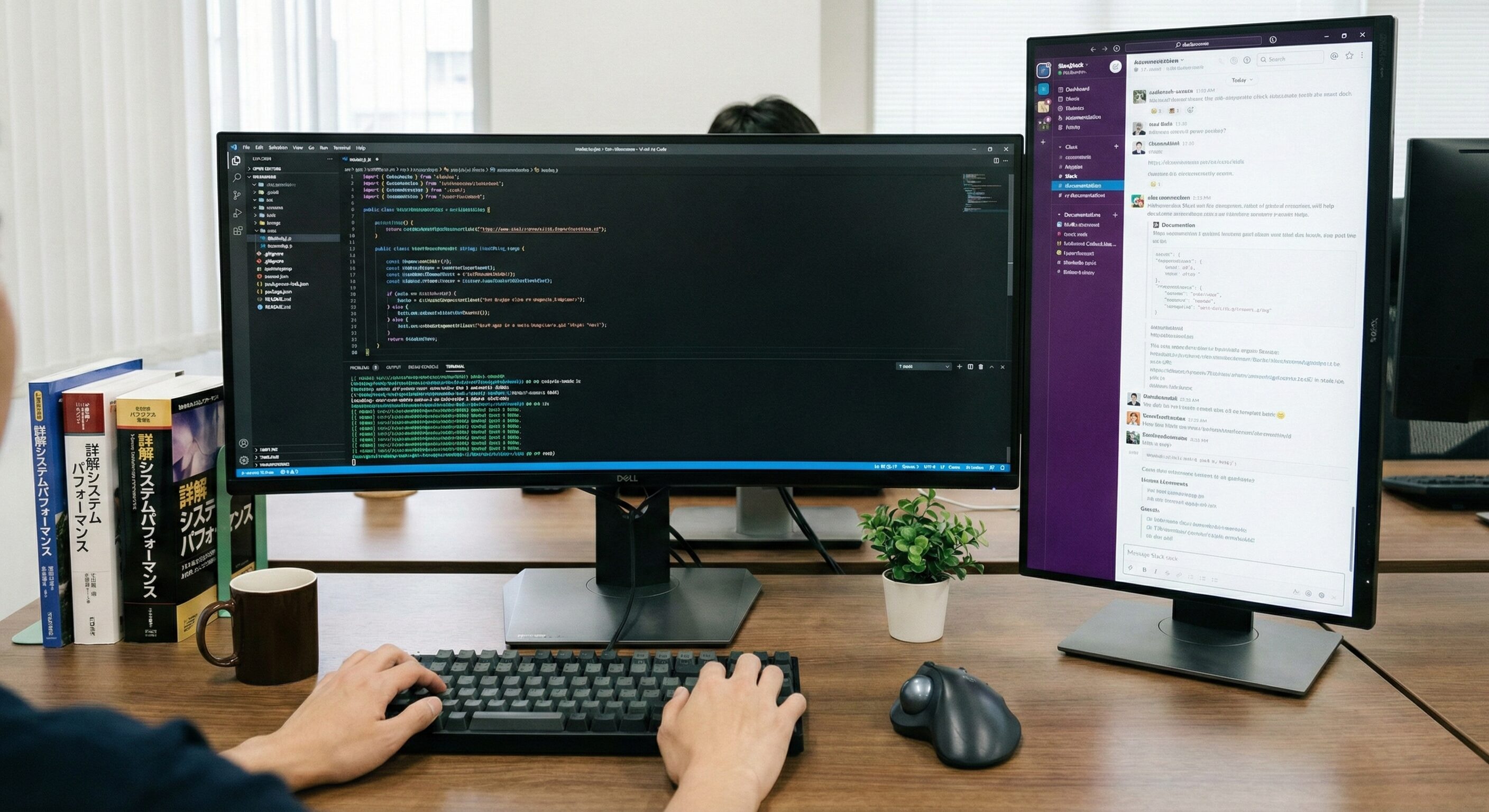 大型モニターにコードエディタとターミナルが表示された開発者のデスクの写真。複数のモニターを使い、ソフトウェア開発に集中している環境。
