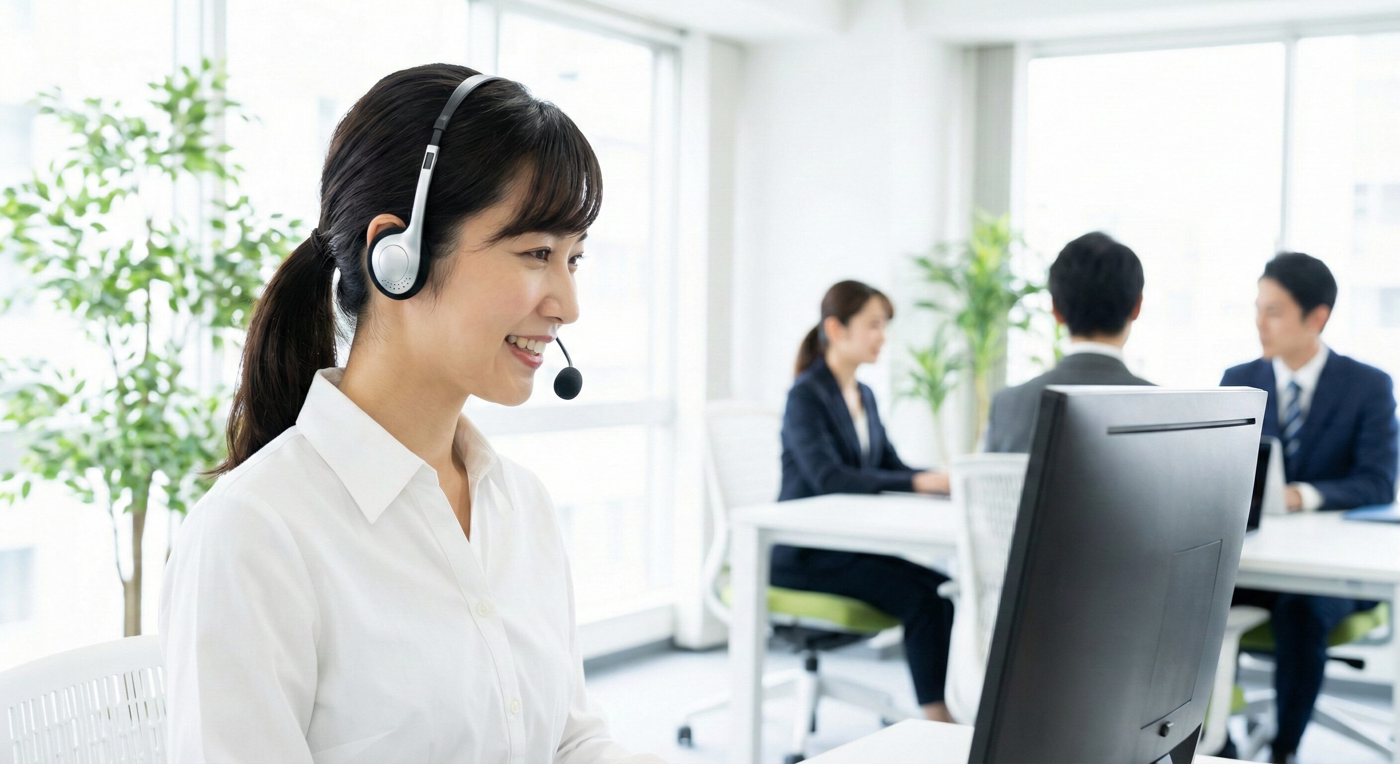 ヘッドセットを装着したオペレーターがモニターを見ながら丁寧に対応している横顔の写真。明るく清潔感のあるオフィス環境。
